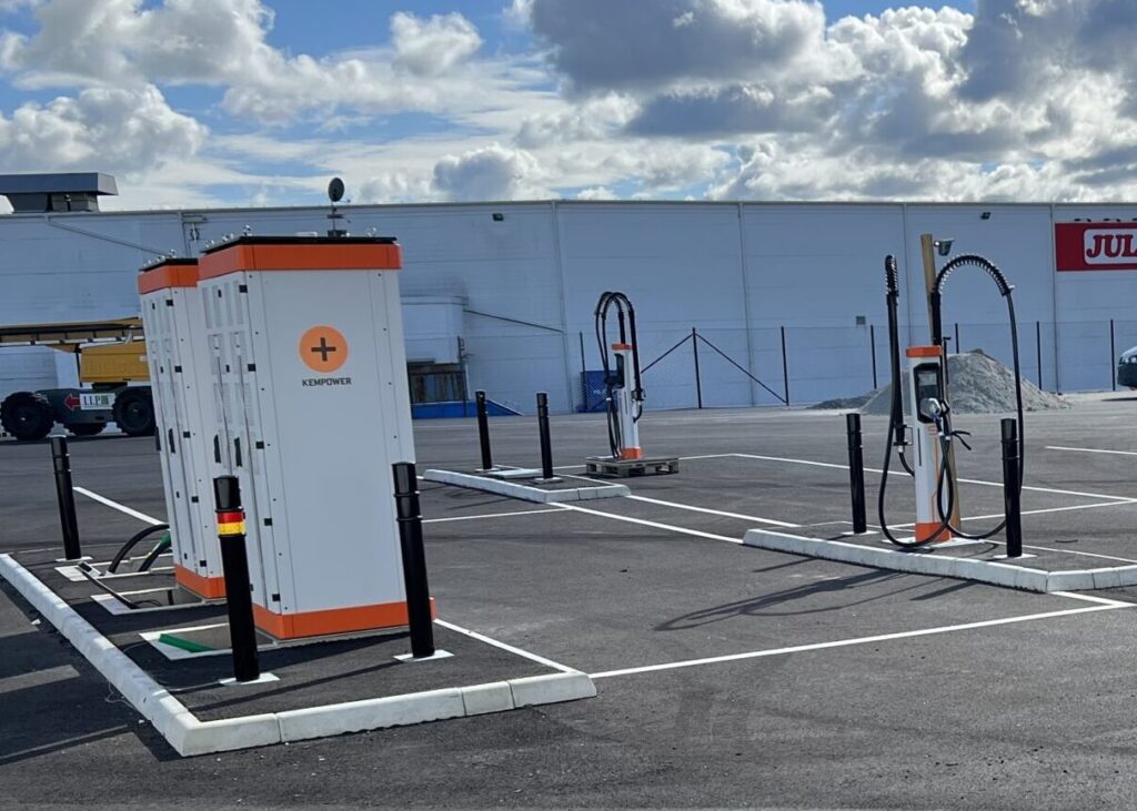 Electric vehicle charging stations in a parking lot under a partly cloudy sky.