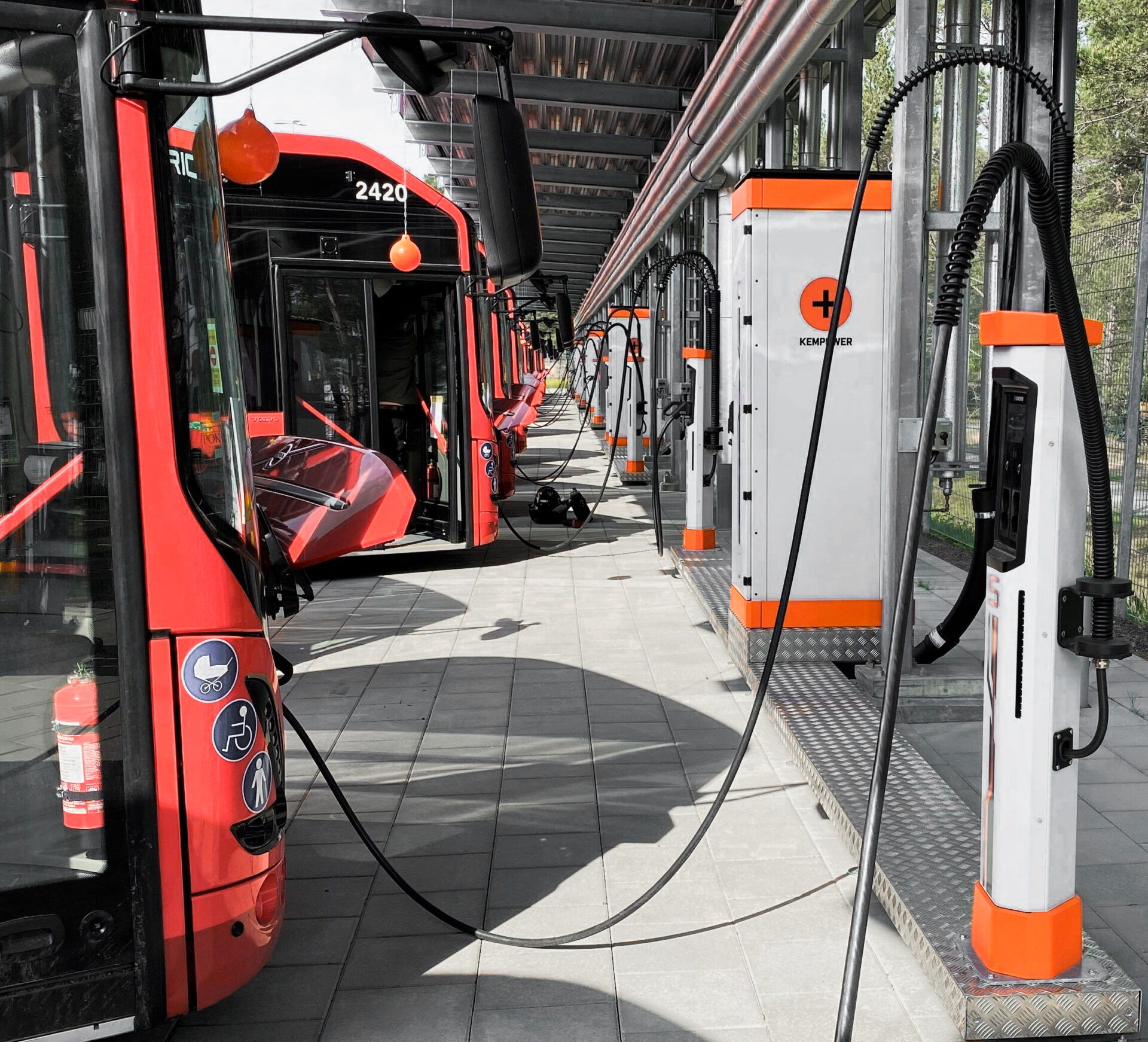 A fleet of electric buses parked at charging stations, powering up for their next route.