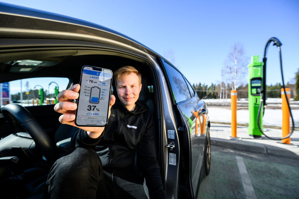 Un uomo mostra lo stato di ricarica della sua auto sul suo cellulare con il sistema di gestione della ricarica EV di Kempower. 