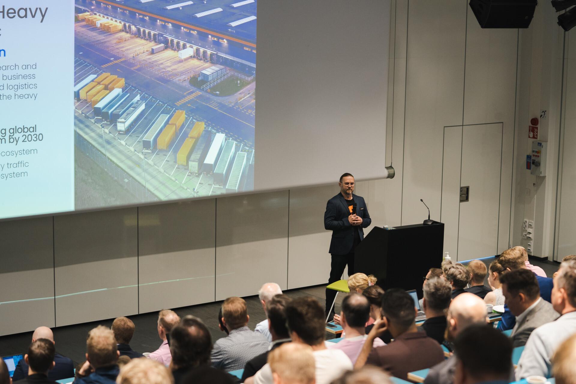 Tommi Rissanen speaks in front of an audience at the Heavy Electric Traffic Ecosystem kickoff event in Lahti, Finland.